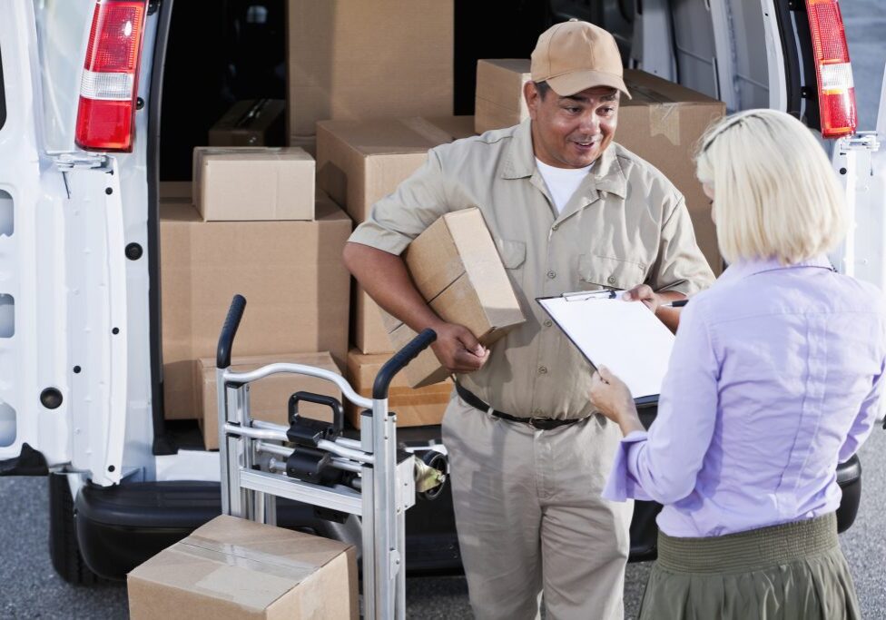 Hispanic man (40s) delivering packages, asking for customer signature.