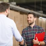 Two businessman shaking hands in warehouse.