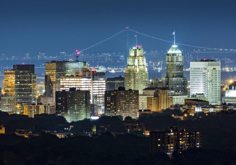 Newark, NJ, skyline on a hazy night with Verrazano Narrows bridge in the background.